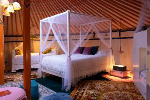 una camera con un letto bianco a baldacchino di L ost in Sensations -Hébergements Insolites et Suites de luxe Spa Sauna Piscine Forêt a Marcenas