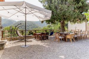 eine Terrasse mit Tischen, Stühlen und einem Sonnenschirm in der Unterkunft La Piana in Pian dʼOrsina