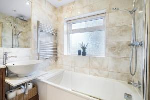 a bathroom with a tub and a sink and a window at Hububb Luxury Eastcote in Eastcote +32 photos