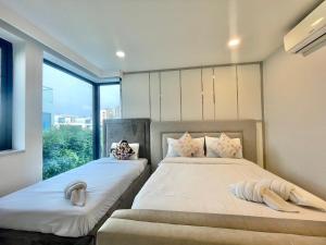 two beds in a room with a window at Pupae Pool Villa Pattaya in Pattaya South