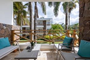 a balcony with chairs and a table and palm trees at Apartamento en Residencial Jardines de Monserrat in Las Terrenas