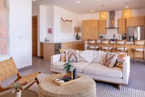 a living room with a white couch and a kitchen at Oceanfront Condo, Stunning Views, Luxury Amenities in El Pescadero
