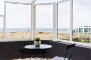 een kamer met een tafel en uitzicht op het strand bij Apartment The Pier in Scheveningen