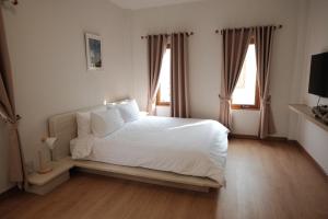 1 dormitorio con 1 cama blanca y 2 ventanas en Wantanee Ville วันทนีย์วิลล์, en Ban Wang Sai