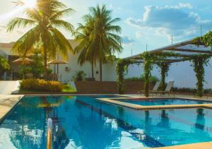 a swimming pool with palm trees in the background at Nord Luxxor Juazeiro do Norte in Juazeiro do Norte