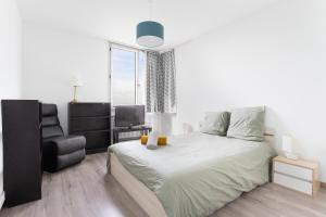 1 dormitorio blanco con 1 cama grande y 1 silla en Appartement proche du Vieux Lille avec une vue exceptionnelle sur la Ville !, en La Madeleine