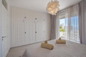 ein weißes Schlafzimmer mit einem Bett und einem Kronleuchter in der Unterkunft 2 Bedroom Apartment - Terrace & Sea View - Los Gigantes in Acantilado de los Gigantes