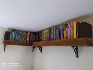 una mensola in legno piena di libri su un muro di The Poets Rest...where comfort and tradition meet. a Moville