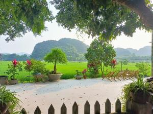 een tuin met een hek en uitzicht op een veld bij Tam Coc Sunshine Homestay in Ninh Binh