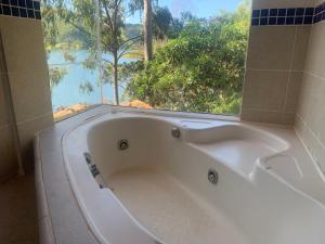 a bath tub with a large window in a bathroom at Casa INTI Refugio Romantico Pague duas noites minimo e a terceira e brinde, menos feriados in Natividade da Serra