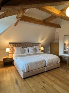 1 dormitorio con 1 cama blanca grande y suelo de madera en La Belle-Croix, en Romont