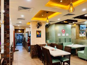 a restaurant with tables and chairs and a person in the background at Hotel Dr Rajkumar International in Bangalore