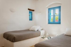 a bedroom with two beds and a blue window at Cemilion in Koufonisia