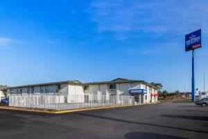 ein Gebäude mit einem Zaun neben einem Parkplatz in der Unterkunft Americas Best Value Inn - Lincoln Airport in Lincoln