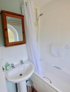 biała łazienka z umywalką i wanną w obiekcie Gryngolet Cottage - with Artist Studio - Crabpot Cottages Sheringham w mieście Aylmerton