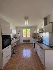 cocina grande con armarios blancos y suelo de madera en Appartement les Mésanges en Le Poët-Laval