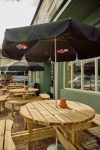 een groep picknicktafels met parasols op een patio bij The Pennine Inn in Kirkby Stephen