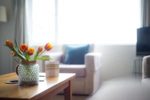 eine Vase mit Blumen auf einem Couchtisch im Wohnzimmer in der Unterkunft Trevose Golf and Country Club in Padstow