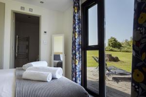 Nunney Lodge في Beckington: غرفة نوم بسريرين وباب زجاجي منزلق