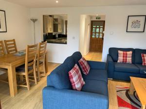 a living room with a blue couch and a table at Selwood Cottage in Beckington