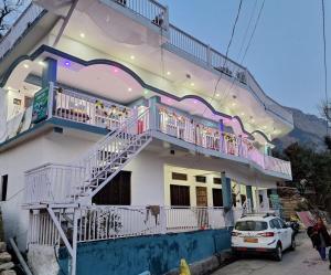 a building with a balcony and a car parked in front at Chandarshila hike homestay in Ukhimath
