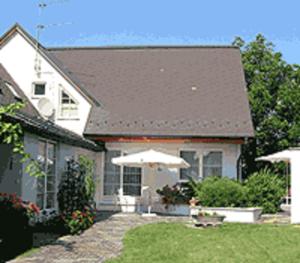 a white house with an umbrella in the yard at Weinlandhaus in Mitterretzbach