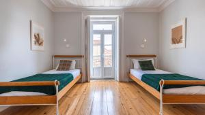 2 camas en una habitación con suelo de madera en Sunny Belém Home by LovelyStay en Lisboa
