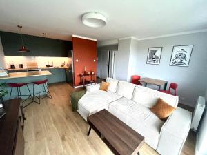 a living room with a white couch and a kitchen at Agapella Apartamenty- Apartament Oliwa Park in Gdańsk