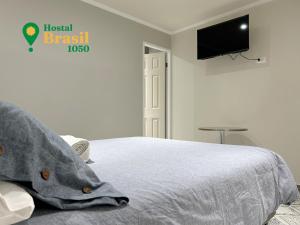 Schlafzimmer mit einem Bett und einem Flachbild-TV in der Unterkunft Hostal Brasil 1050 in La Serena