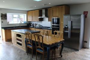 a kitchen with a table and a stainless steel refrigerator at Westleigh House in Fishbourne