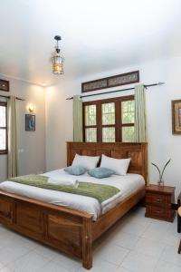 Un dormitorio con una gran cama de madera con almohadas azules en Green Square Grove - Entire House, en Kampala