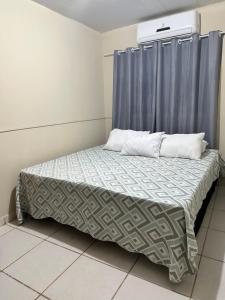 a bed in a room with a blue curtain at Hotel Nossa Senhora de Lourdes in Trindade