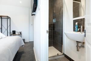 a bathroom with a shower and a sink next to a bed at The Nook - Self Serviced Accommodation in St Ives