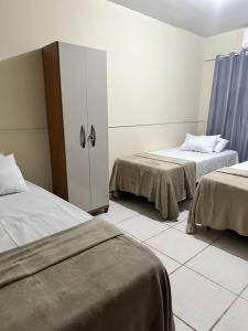 um quarto com duas camas e um armário em Hotel Nossa Senhora de Lourdes em Trindade