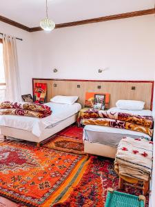 three beds in a room with a rug at Gite Panorama in Imlil