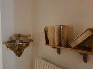 a shelf with books on a wall next to a radiator at B&B La finestra sul bosco in Serralunga di Crea
