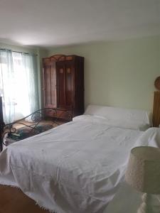 1 dormitorio con cama blanca y armario de madera en B&B La finestra sul bosco, en Serralunga di Crea