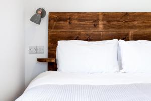 a bed with white pillows and a wooden headboard at The Nook - Self Serviced Accommodation in St Ives
