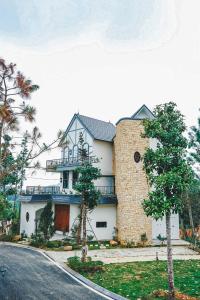 ein großes weißes Haus mit einem Baum davor in der Unterkunft Valentina Castle - Melorita Hòa Lạc in Hanoi