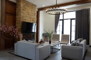 ein Wohnzimmer mit zwei Sofas und einem Fernseher in der Unterkunft Valentina Castle - Melorita Hòa Lạc in Hanoi