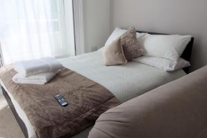 uma cama com almofadas e um controlo remoto em 1 bedroom apartment - The Opal em Cheltenham