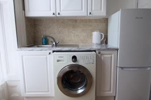 uma cozinha com uma máquina de lavar roupa e um lavatório em 1 bedroom apartment - The Opal em Cheltenham