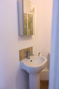uma casa de banho com um lavatório e um espelho em 1 bedroom apartment - The Opal em Cheltenham