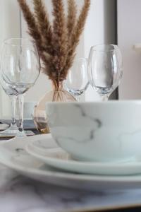 1 bedroom apartment - The Opal في تشلتنهام: طاولة مع ثلاثة كؤوس من النبيذ وصحن مع النباتات