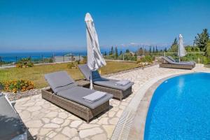 a swimming pool with two lounge chairs and an umbrella at Villas Goudis in Tsoukalades