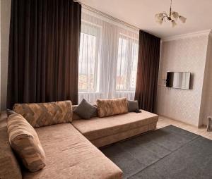 uma sala de estar com um sofá e uma grande janela em Двухкомнатная квартира на набережной em Astana