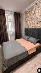 1 dormitorio con 1 cama grande y pared de roca grande en Двухкомнатная квартира на набережной, en Astana