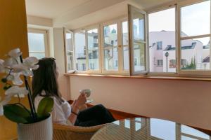a woman sitting in a chair looking out the window at Hotel Wilder Mann in Passau +48 photos