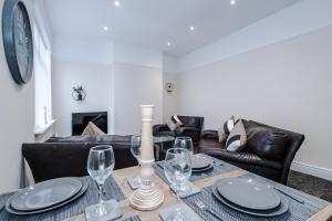 a dining room table with wine glasses and a couch at Cosy Modern 3-BR Apartment - Sleeps 5 in Liverpool
