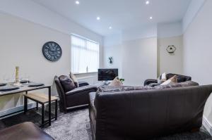 a living room with two couches and a clock on the wall at Cosy Modern 3-BR Apartment - Sleeps 5 in Liverpool